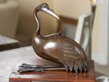 une statue représentant une grue posée sur un socle en bois
