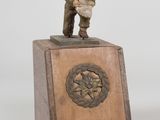 statue of a man in uniform standing on top of a wooden pedestal