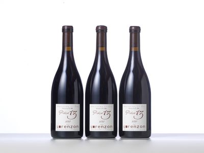 three bottles of red wine are lined up on a table