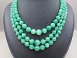 a green beaded necklace on a black mannequin