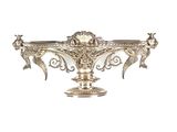 un plat ancien en argent orné d'oiseaux, posé sur un socle