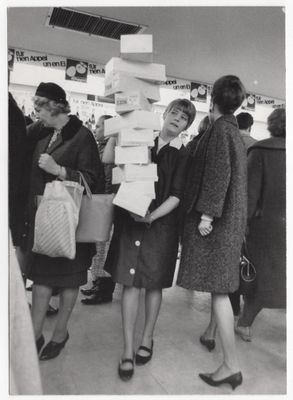photo en noir et blanc d'un groupe de femmes debout autour d'une pile de cartons
