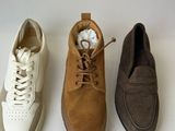 three pairs of men ' s shoes are lined up on a white surface