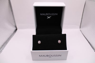 Les boucles d'oreilles se trouvent dans la boîte posée sur la surface blanche.