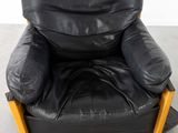 a black leather chair with wooden legs in a room
