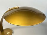 a close up of a gold desk lamp on a white surface