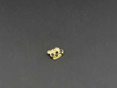 a close up of a gold skull charm on a black surface
