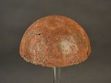 an old helmet on a metal stand against a gray background
