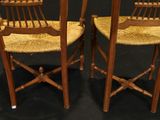 pair of wooden chairs with woven seats on a black background