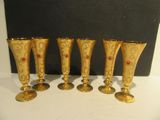four gold wine glasses with red stones on them sitting on a table