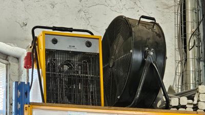 un grand ventilateur posé sur une étagère, à côté d'un radiateur