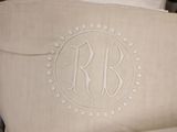 a pillow with a monogram on it sitting on a bed