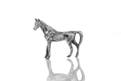 une figurine de cheval en argent posée sur une surface réfléchissante