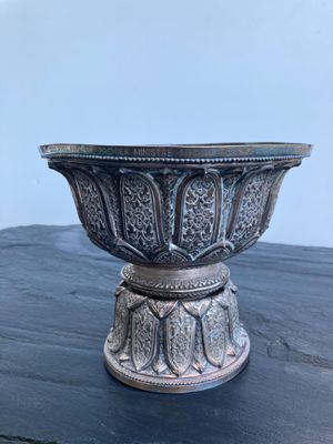 un bol ancien en argent posé sur une table en bois, sur fond blanc