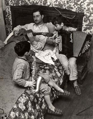 black and white photo of a man playing an accordion with a group of children