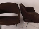pair of brown chairs with chrome legs against a white wall