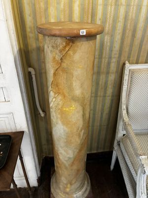une grande colonne de marbre surmontée d'un élément en bois, dans une pièce