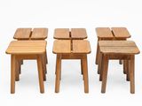 quatre petits tabourets en bois placés les uns à côté des autres sur une surface blanche