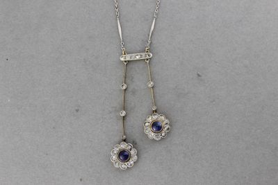 un gros plan sur un collier orné d'un motif floral et d'une pierre bleue