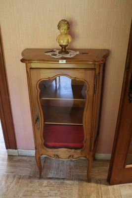 un petit meuble en bois surmonté d'un coussin rouge