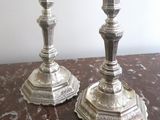 two silver candlesticks sitting on a marble table