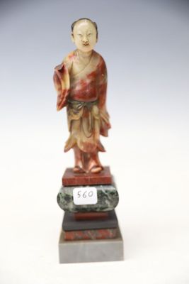 une image représentant la statue d'un homme vêtu d'une robe rouge, posée sur un socle