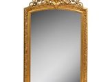 an ornate gold mirror with a white background and reflection