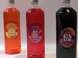 trois bouteilles de boissons aux saveurs différentes posées sur une surface blanche