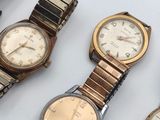 several watches are sitting on a white surface with a red strap around them