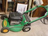 une tondeuse à gazon verte posée par terre dans un garage