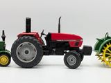 three toy tractors on a white surface with a white background