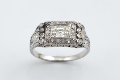 une bague en or blanc sertie d'un diamant taille princesse entouré de petits diamants