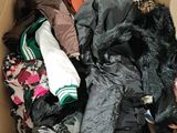 a cardboard box filled with clothes and a pile of clothes