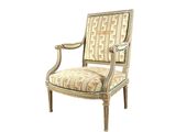 La chaise est en bois et son assise est rembourrée et ornée d'un motif.