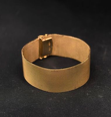 gros plan d'un bracelet en or sur une surface noire