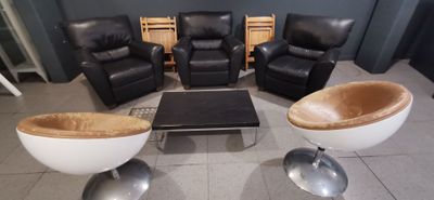 plusieurs chaises et une table basse dans une pièce dont l'un des murs est noir