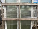 a stack of windows sitting on a pallet in a yard
