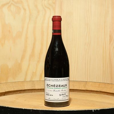 a bottle of wine sitting on top of a barrel