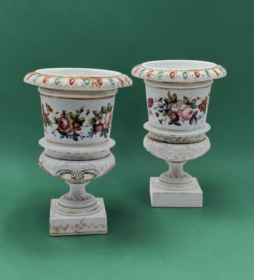 two white vases with floral designs on them on a green background