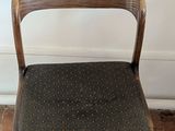 a wooden chair with a black seat on a brick floor