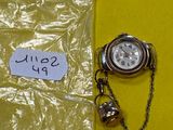 une montre de poche et une chaîne posées sur une table jaune