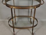 an image of a brass and glass bar cart on wheels