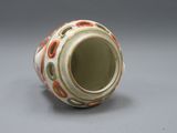 un vase blanc orné de motifs orange et verts