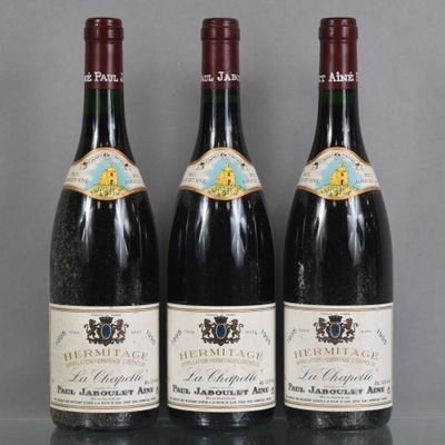 Trois bouteilles de vin sont alignées sur une table en verre