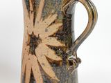 a brown and black vase with a flower on it