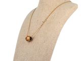 gold plated necklace with a red glass bead on a mannequin neck