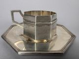 a silver cup and saucer on a silver plate