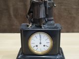 a statue of a man sitting on a table with a clock