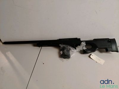 un fusil posé par terre, muni d'une étiquette