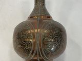 a metal vase that is sitting on a white surface